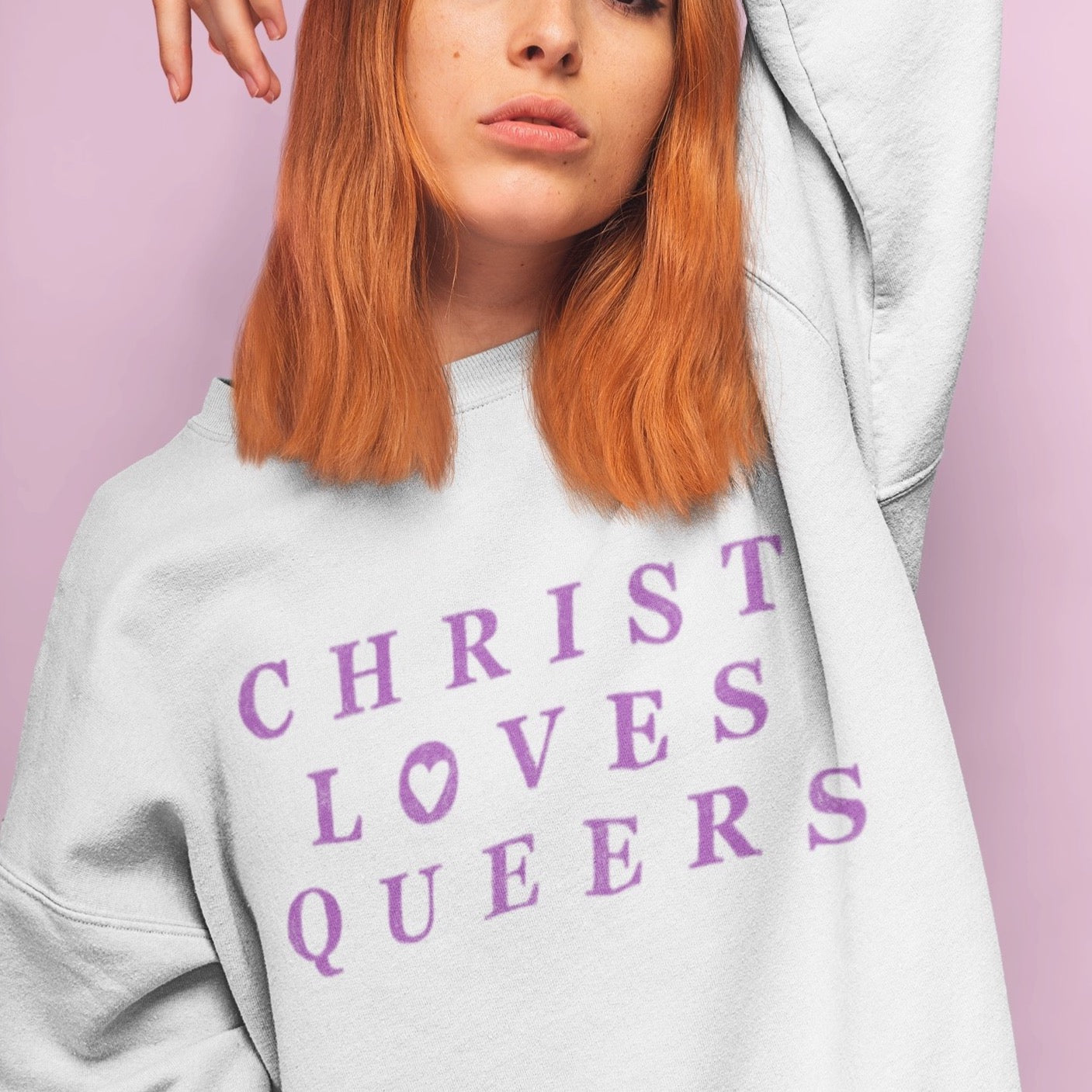white pride sweatshirt that says Christ Loves Queers In Purple Writing- Shop pride themed shirts, feminist apparel and dump him shirts