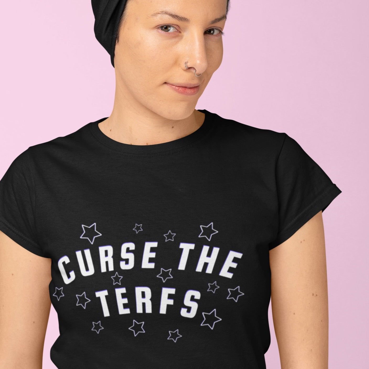 Black unisex pride themed shirt that says curse the terfs in bold white writing with dark purple blue accents. surrounded by stars. Shop Feminist Trash for clothing for pride