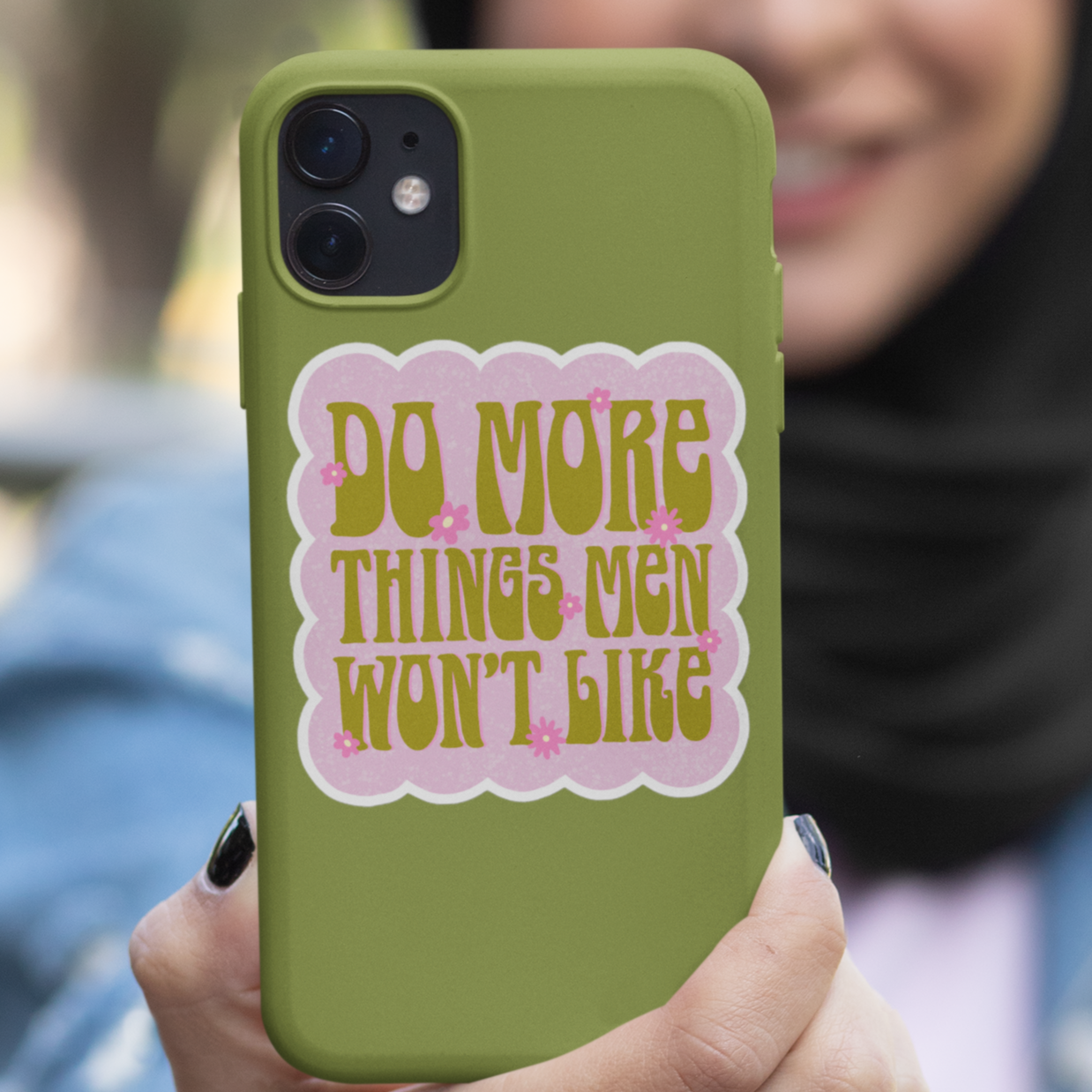 funny feminist sticker that says do more things men won't like in a lime army green 70s retro font with pink flower details and a bubble pink background.