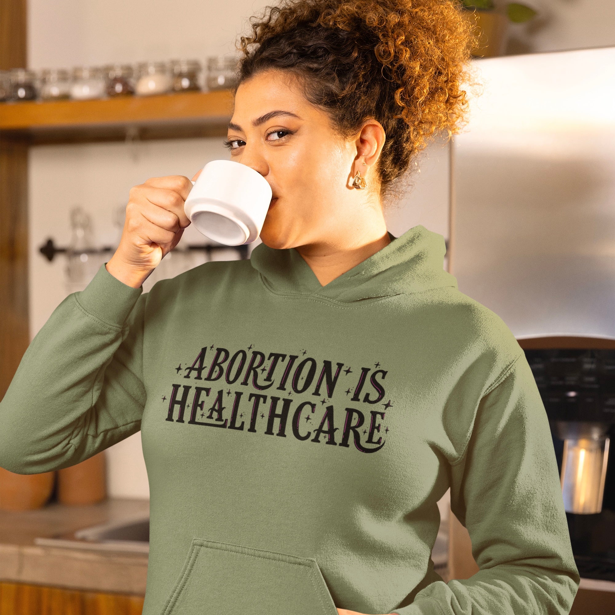 Army green feminist hoodie that says abortion is healthcare in black and pink hand lettered text- shop feminist apparel