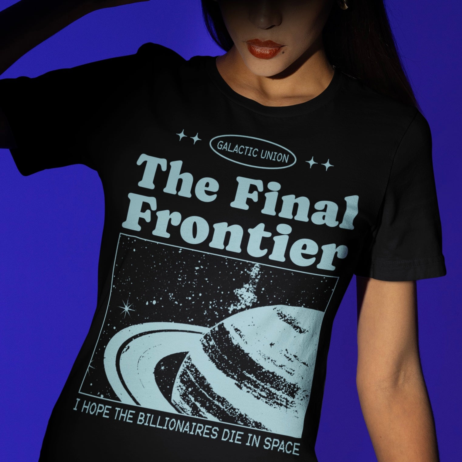 political t-shirt that says " the final frontier, i hope the billionaires die in space in light blue retro writing featuring a space satellite image of Saturn. shop feminist trash for political clothing, feminist t-shirts and pride merch.