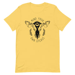 yellow feminist tshirt that says mind your own uterus featuring a black witchy illustration of a uterus- shop feminist shirts