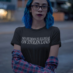 black political t-shirt that says no human is illegal on stolen land in white thin writing. Shop feminist trash store for political clothes and feminist shirts