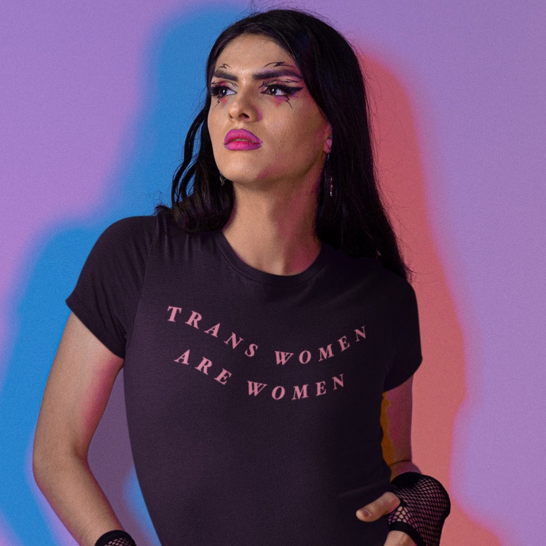Black unisex pride tee that says tans women are women in orange wavy writing