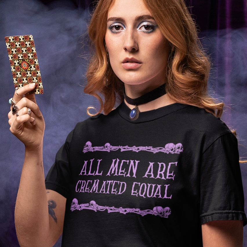 black witchy feminist tshirt that says all men are cremated equal in purple writing. Shop feminist trash for funny feminist t-shirts and witchy outfits