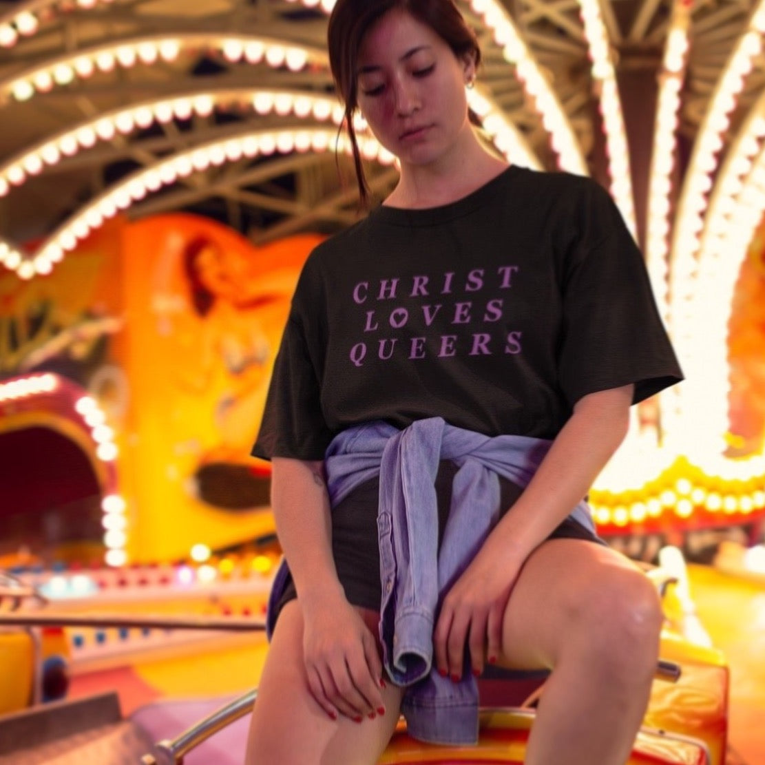 Black Feminist T-Shirt that says christ loves queers in purple writing- define pride with our pride themed shirts and pride merch