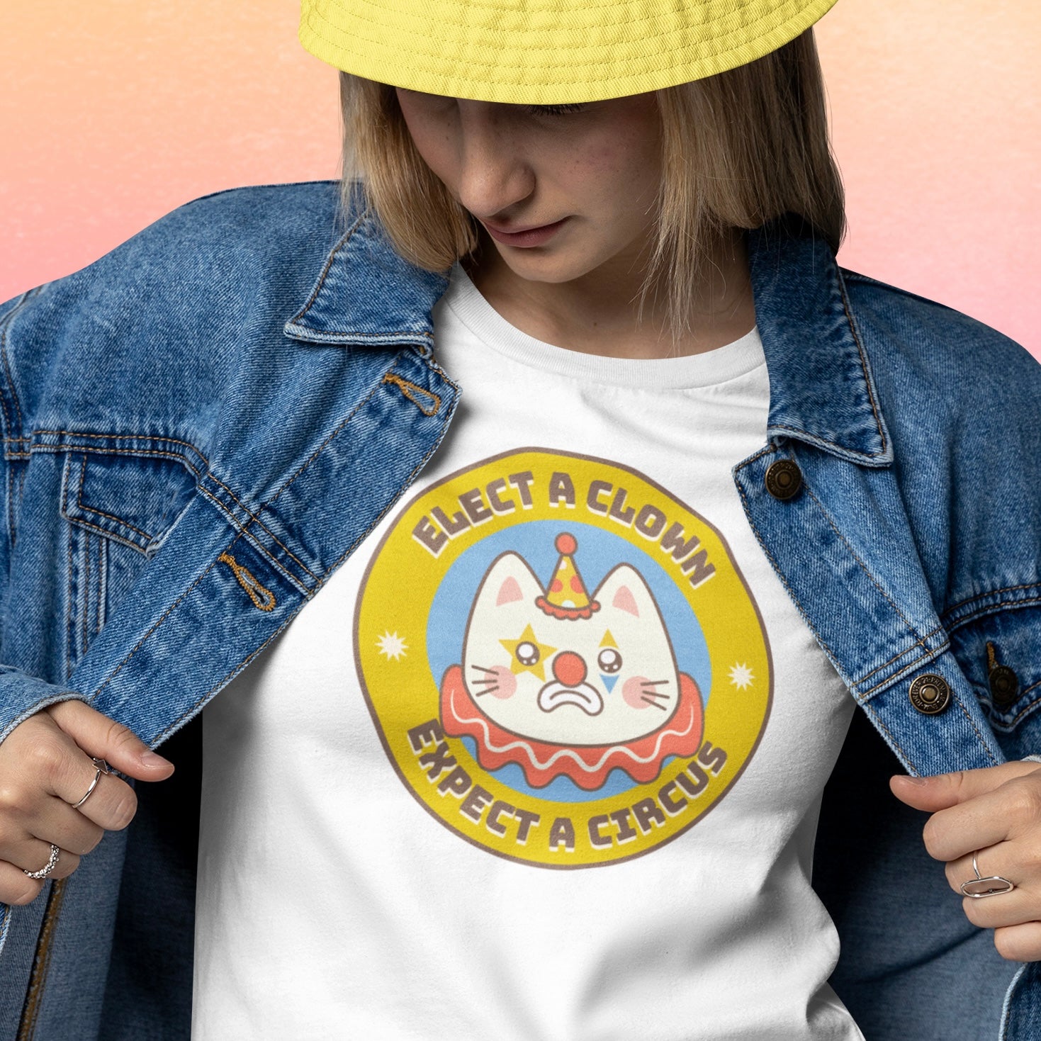 white political t-shirt that says elect a clown expect a circus in brown writing featuring a clown illustration of a cat- shop feminist trash for political clothing, feminist tshirts and pride merch