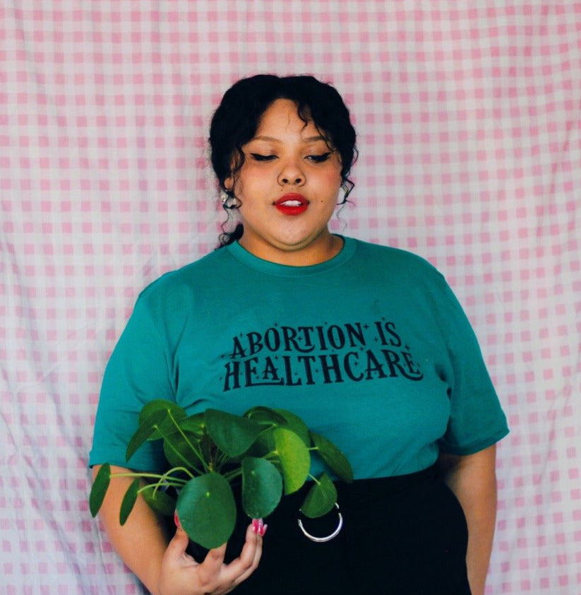 Kelly green feminist shirt featuring 'Abortion is Healthcare' message in black hand lettering- Shop feminist shirts