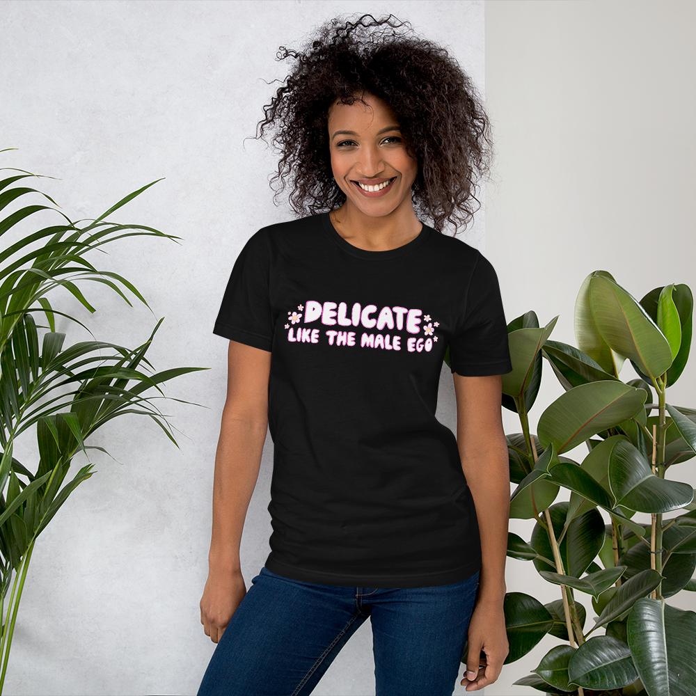 black feminist shirt that says 'Delicate Like the Male Ego in white bubble writing with pink accents and small daisy illustrations- shop feminist tees, dump him shirts and political clothes.