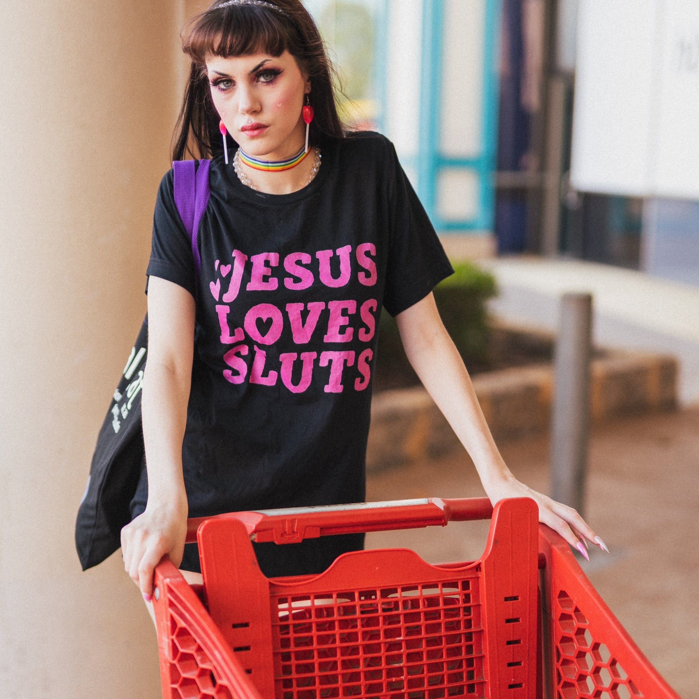 Black feminist t-shirt that says 'Jesus Loves Sluts' in red hand lettered writing- shop Feminist Trash for feminist apparel, political clothing, acab t-shirts, pride outfits and dump him shirts.