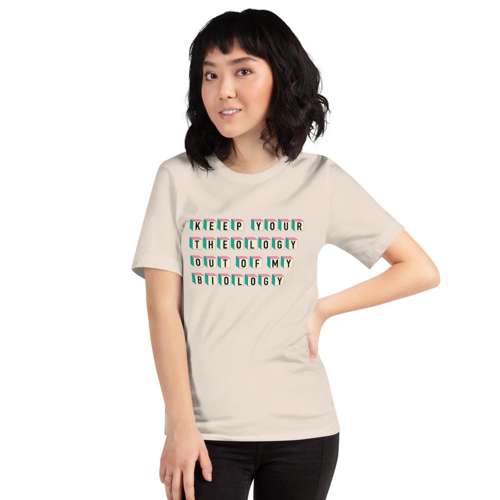 Soft cream feminist t-shirt boldly declaring "Keep Your Theology Out of My Biology- shop feminist trash store for political clothes, pro choice shirts and pride merch