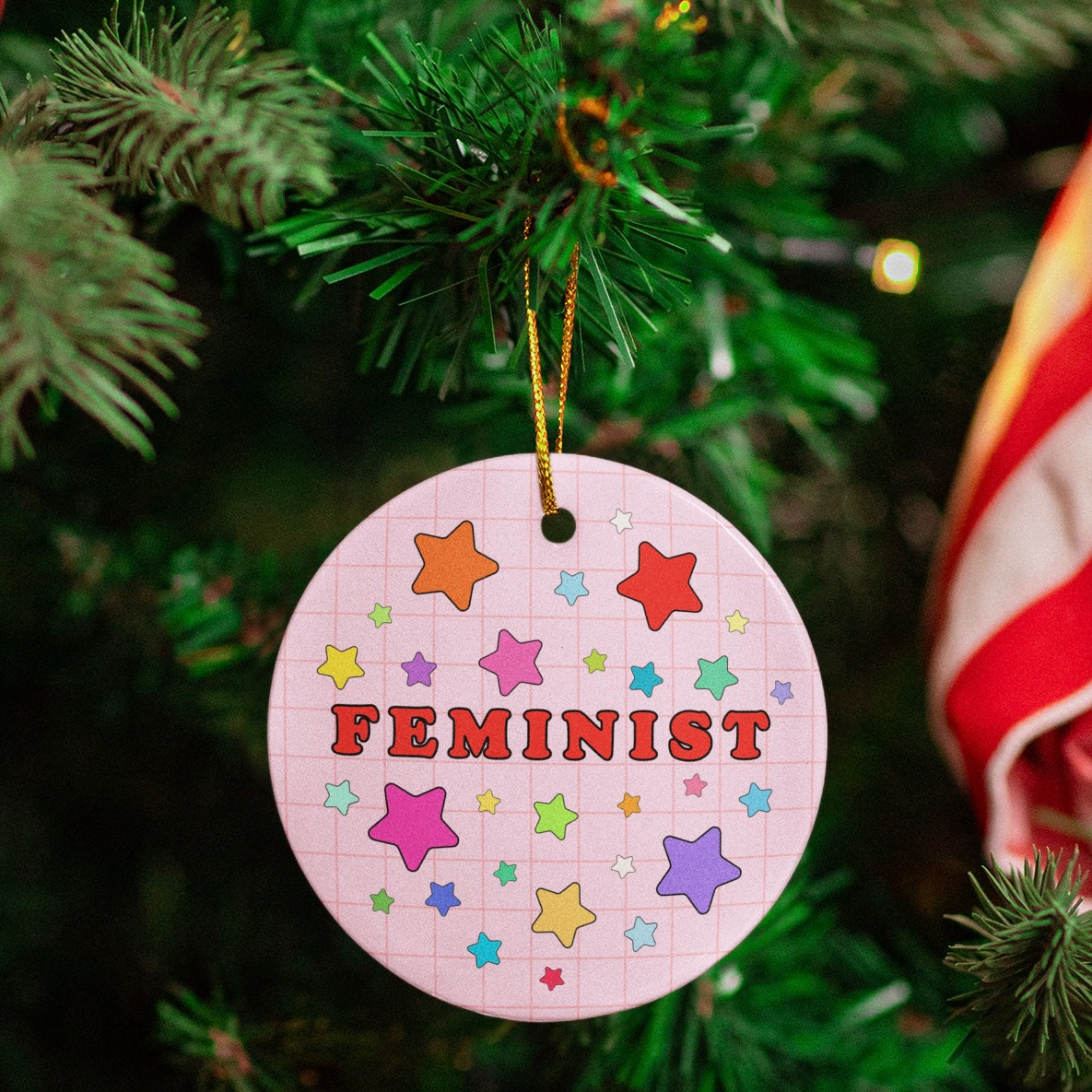 circle ceramic christmas ornament that says feminist surrounded by stars- shop feminist trash for feminist merch and christmas decorations