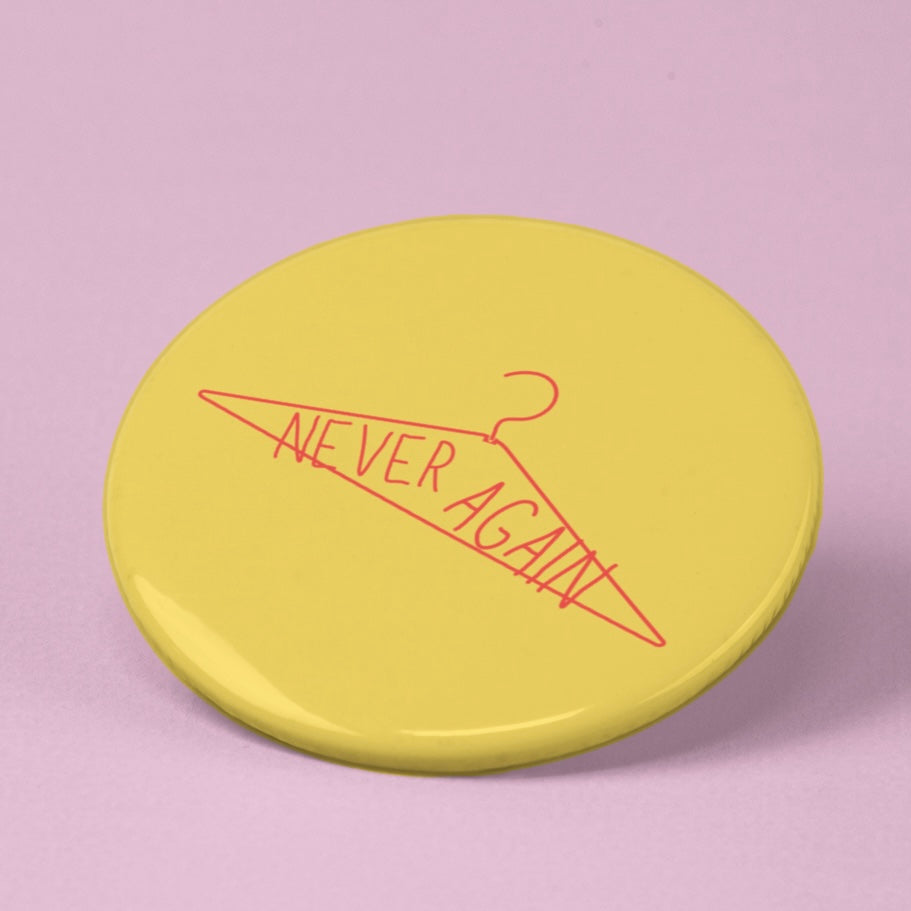feminist pin that says never again inside a red coat hanger- shop feminist trash for pro choice pins and feminist tshirts