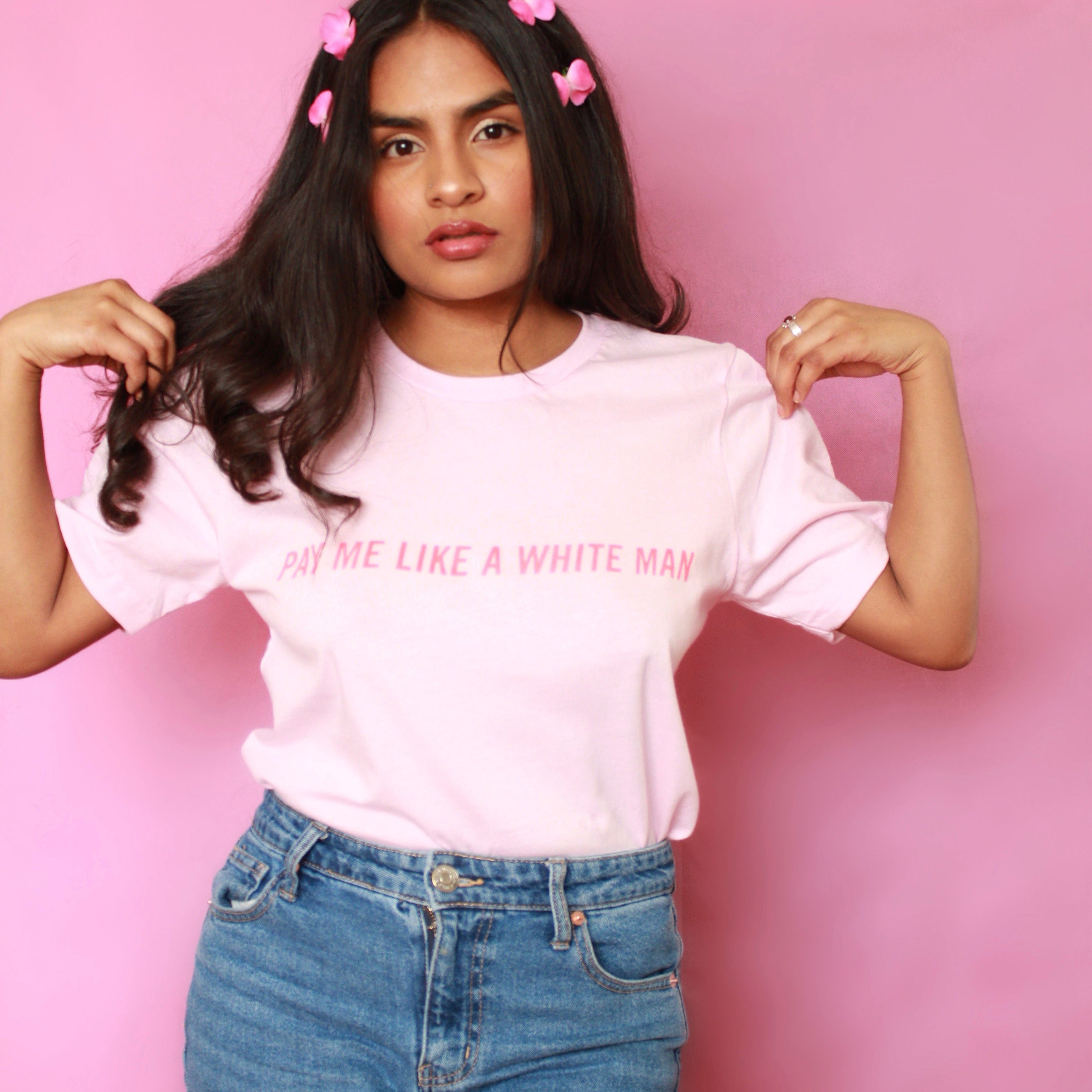 Pink unisex feminist t shirt that says Pay Me Like A White Man in red uppercase writing. Shop Feminist Trash for funny t shirts for women, cat shirts, and presents for book lovers
