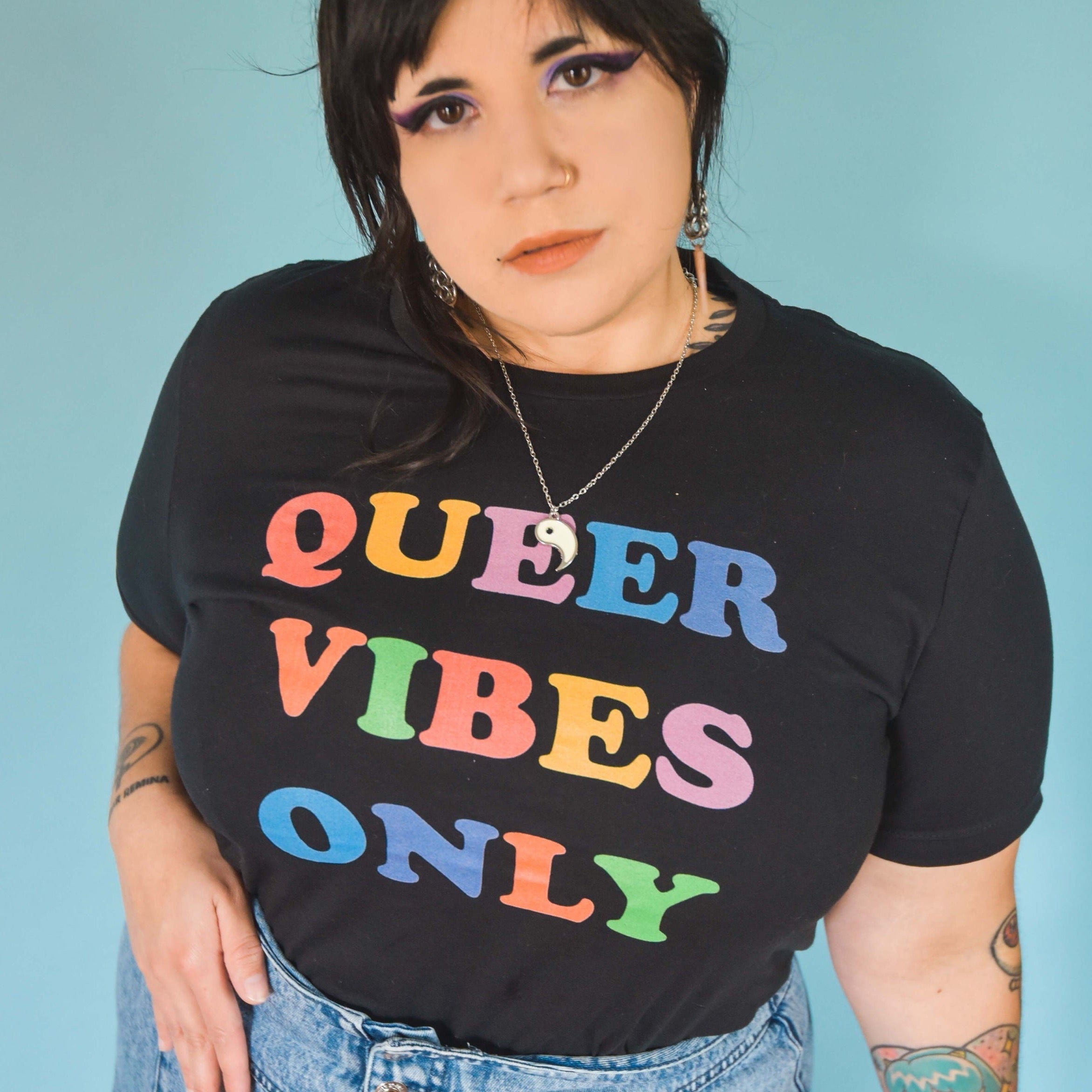 Pride t-shirt in black proclaiming "Queer Vibes Only" in rainbow writing- define pride with our pride tees, political clothing, pride clothing, pride outfits and dump him shirts