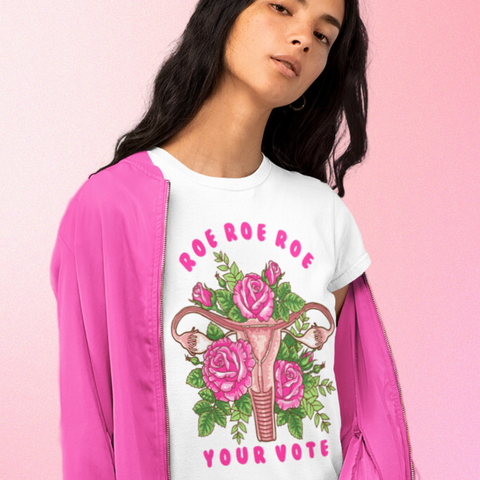 white feminist tshirt that says roe roe roe your vote in pink writing- featuring an uterus floral illustration. Shop feminist trash store for feminist tshirts and political clothes.