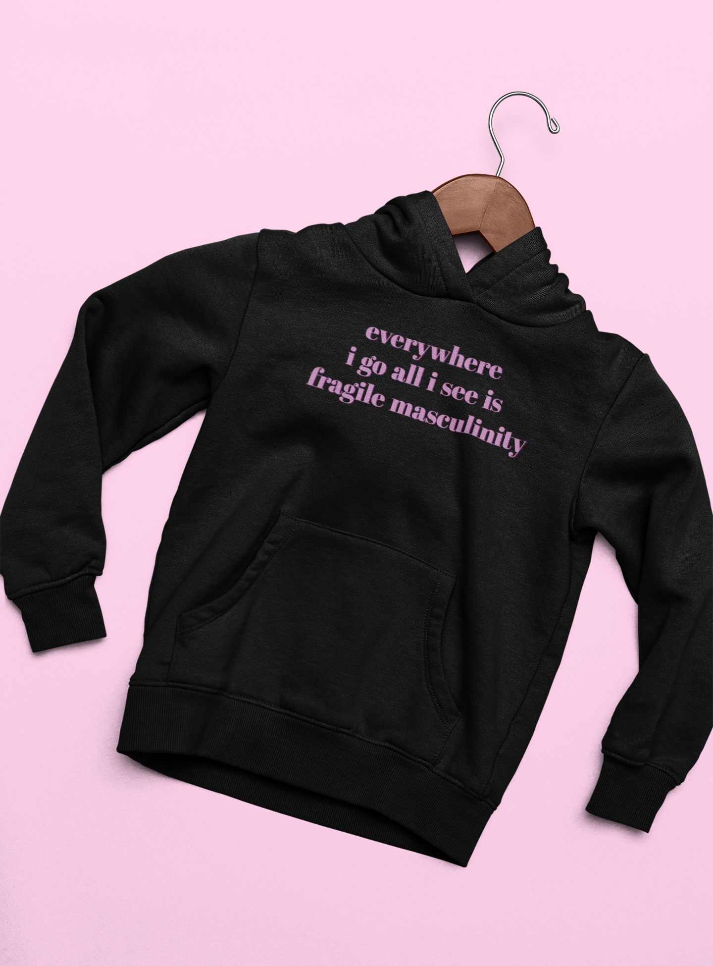 Black feminist hoodie that says Everywhere I Go All I See Is Fragile Masculinity in purple lowercase font Shop Feminist apparel and dump him shirts