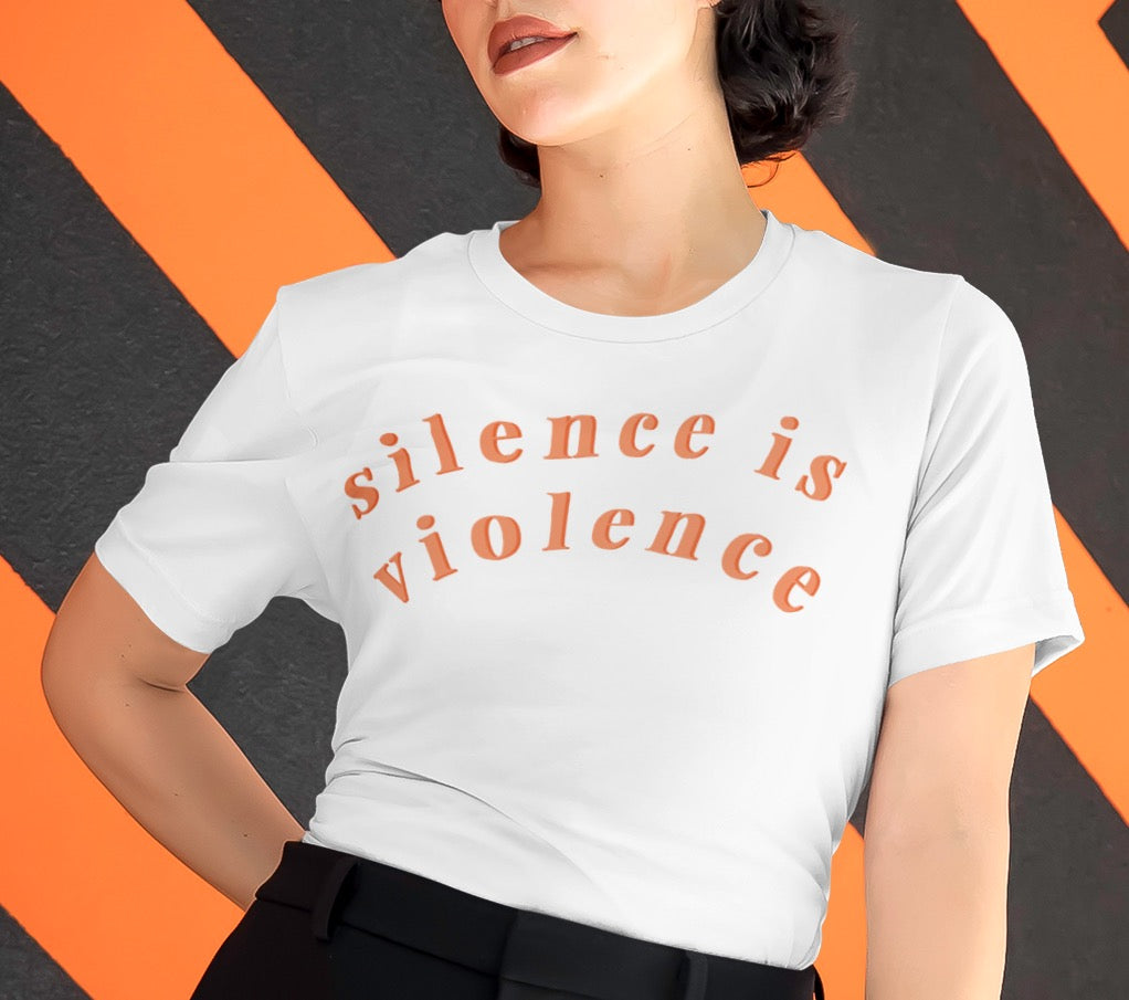 White feminist shirt that says silence is violence in bold orange lowercase writing- shop feminist shirts