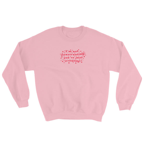 pink feminist sweatshirt that says I’m Not Menstruating You’re Just Irritating in red wavy writing with stars surrounding it- define feminism with our feminist apparel