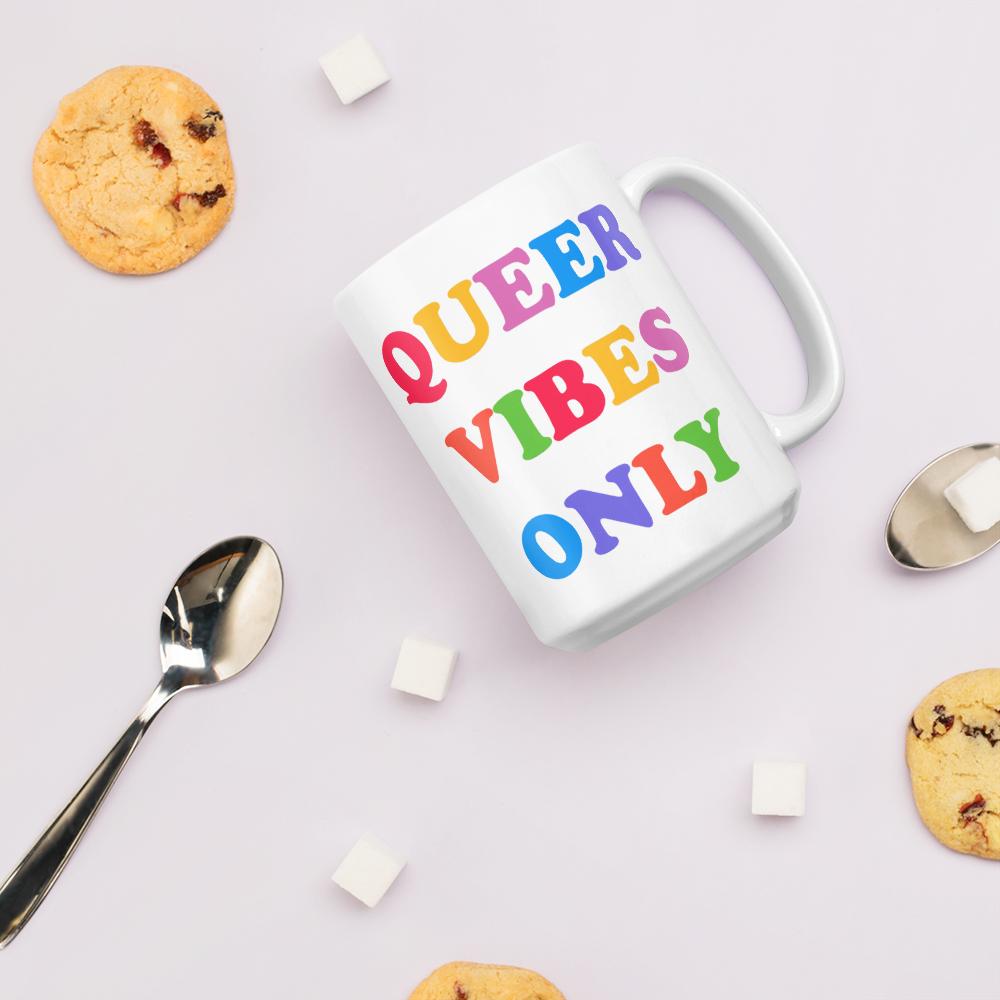 15 oz Pride mug that says Queer Vibes in rainbow retro writing- shop feminist trash for pride clothing, political t shirts, feminist apparel and dump him shirts
