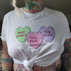 White feminist tshirt that says Why Can’t You Find The Clit? in three candy hearts- shop feminist apparel and dump him shirts