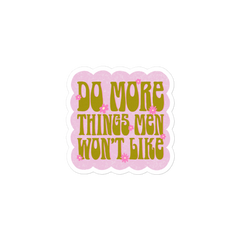 3x3 Feminist sticker with the message 'Do More Things Men Won’t Like' in a lime army green 70s retro font, accented with pink flower details and set against a bubble pink background.