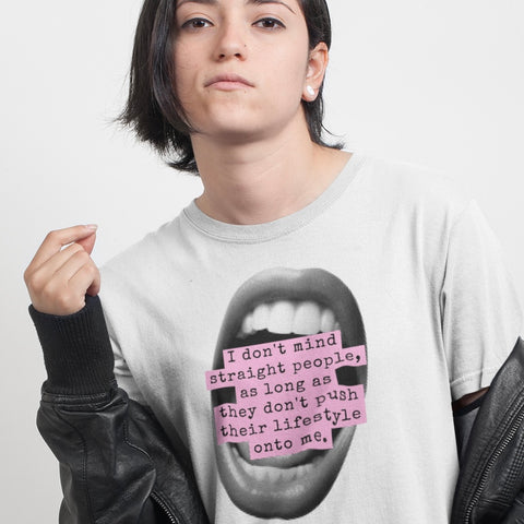 Close-up portrait of a person with dark hair wearing the white "I don't mind straight people" activist graphic tee, styled with a black leather jacket shrugged off their shoulders.