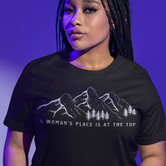 black feminist t shirt that says a woman's place is at the top in white writing featuring a white outline of a  mountain range 