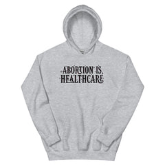 grey feminist hoodie that says abortion is healthcare in black bold hand lettering with pink accents