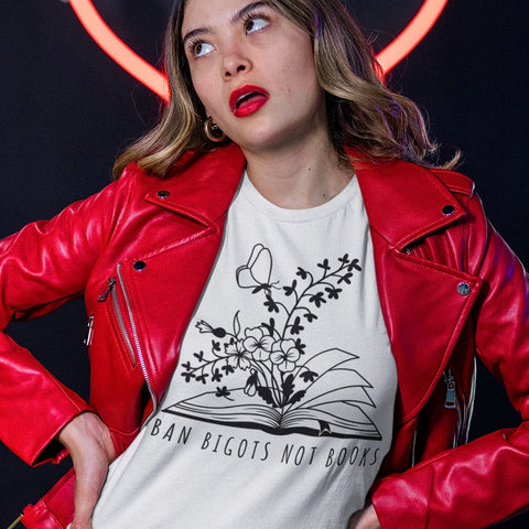 white political t-shirt that says ban bigots not books in black writing featuring an illustration of an opening book with flowers blooming out of it and one butterfly- shop feminist trash for feminist t-shirts, political clothes and dump him shirts