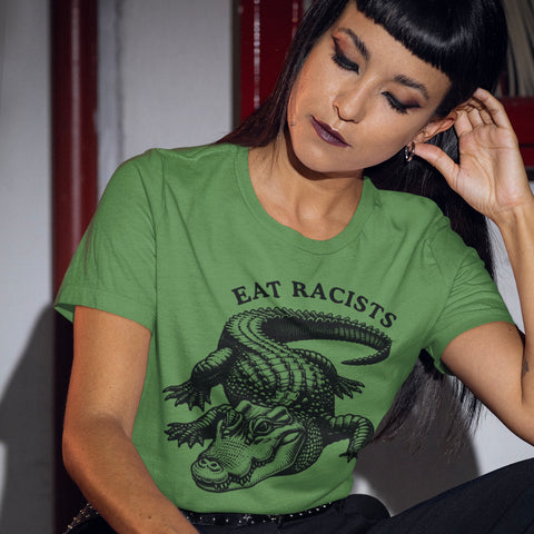 green Anti Alligator Alcatraz political t-shirt that says eat racists in black writing featuring a black illustration of an alligator/crocodile. Shop feminist trash for political clothing and anti racists tees 
