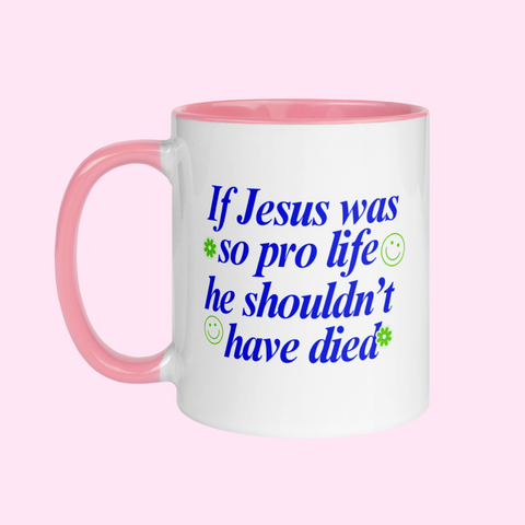White feminist mug with pink interior and handle, featuring the phrase "If Jesus was so pro-life, he shouldn't have died" in blue lettering, accented with cute green illustrations- Shop Feminist Ceramics
