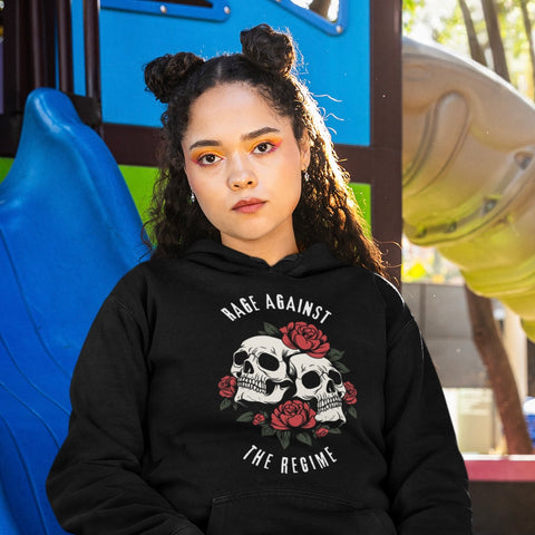 black political sweatshirt that says rage against the regime in white writing- featuring two sculls surrounded by roses. Shop feminist trash for political clothing and witchy outfits