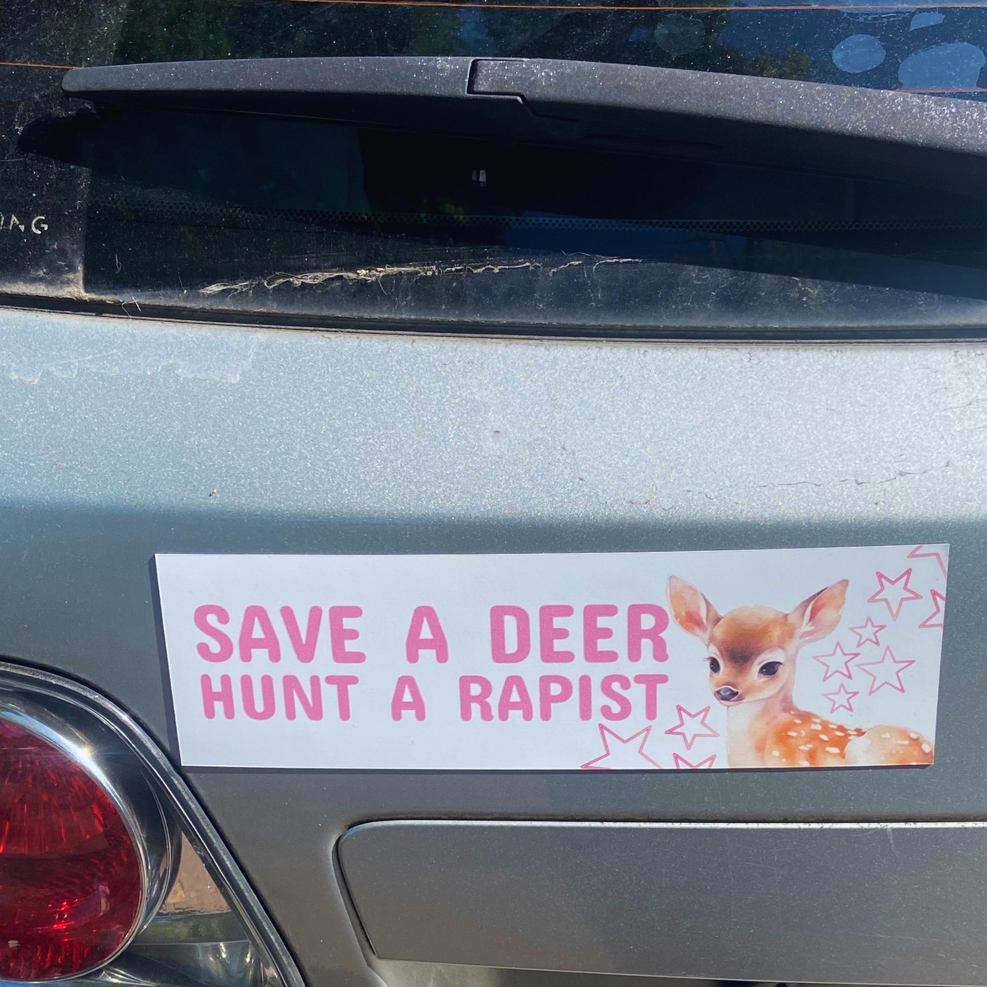 Feminist car magnet that says save a deer hunt a rapist in pink writing. Featuring a watercolour illustration of a Bambi style deer. Shop feminist trash for feminist apparel, magnets and stickers 