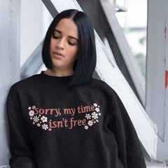 Black feminist sweatshirt that says sorry my time isn't free in orange writing surrounded by white and orange retro flowers- shop feminist apparel, political clothes and dump him shirts