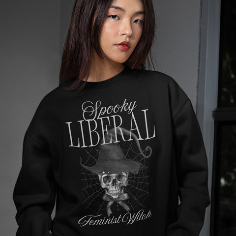 Black feminist sweatshirt that says spooky liberal feminist witchy in white writing- featuring a skull witch watercolour illustration. Shop feminist trash for witchy outfits and feminist clothing