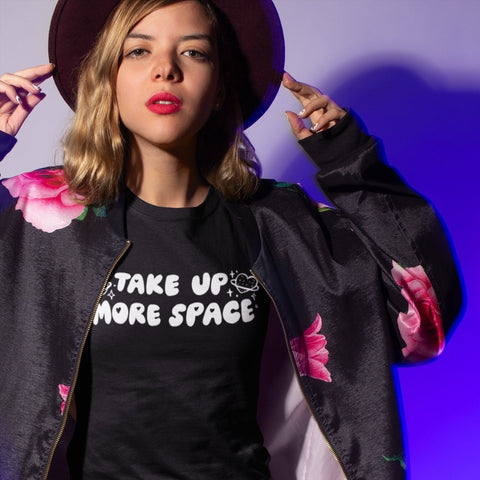 Black feminist tshirt that says take up more space in white bubble writing. Shop feminist apparel