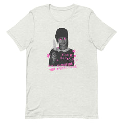 An ash grey unisex cotton political t-shirt laid flat, featuring an edgy cut-and-paste zine art design of a girl holding a kitchen knife with pink stars over her eyes and the slogan "Your God Wants You to Sacrifice the Trillionaire.