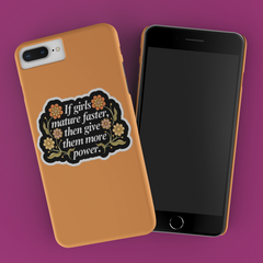 feminist sticker that says if girls mature faster than give them more power in white writing surrounded by orange floral illustrations on a black background- shop feminist trash for feminist stickers 