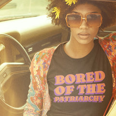 black feminist shirt that says bored of the patriarchy in orange and purple retro writing- Shop feminist trash, one of the best online stores to buy feminist shirts and political clothing.