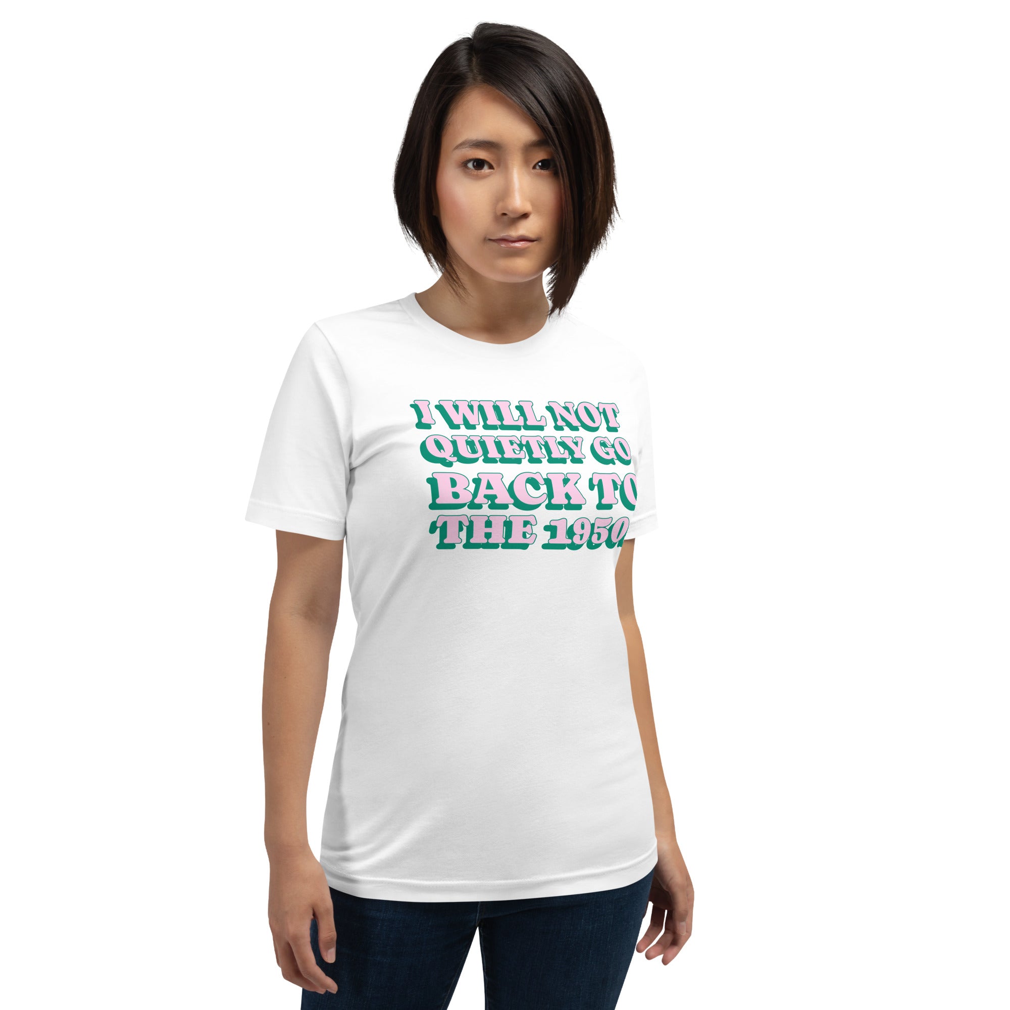 A person wearing the white "I WILL NOT QUIETLY GO BACK TO THE 1950s" Feminist Trash t-shirt. The shirt features a pink and green retro-style graphic, ideal for activist-themed outfits.