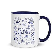 A "Radicalized by Basic Decency" political mug sitting on a modern office desk next to a laptop and a houseplant, illustrating feminist home decor and activist office accessories.