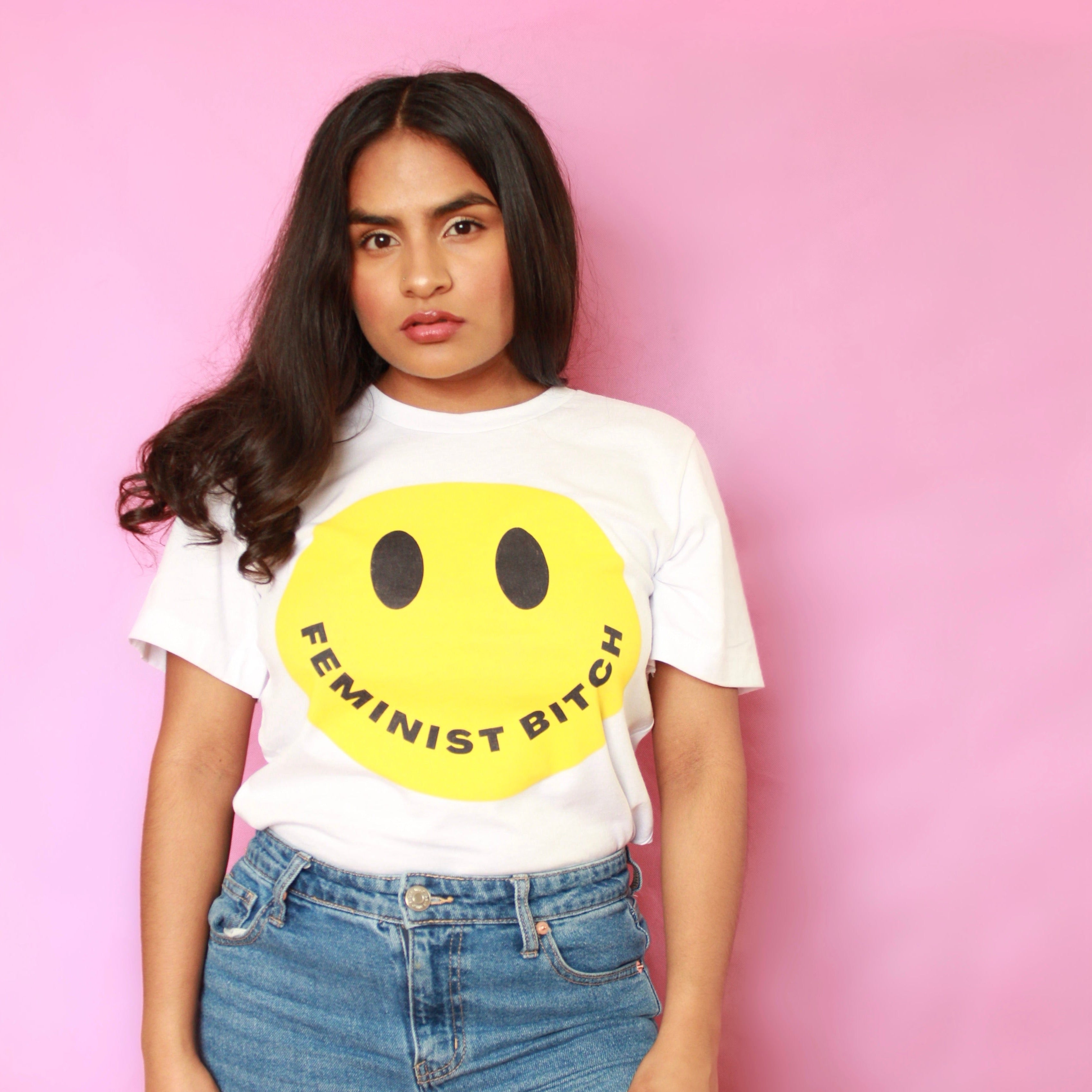 Empowering white feminist shirt featuring the message "Feminist Bitch" with a yellow smiley face
