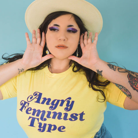 Yellow feminist t-shirt boldly proclaiming "Angry Feminist Type."