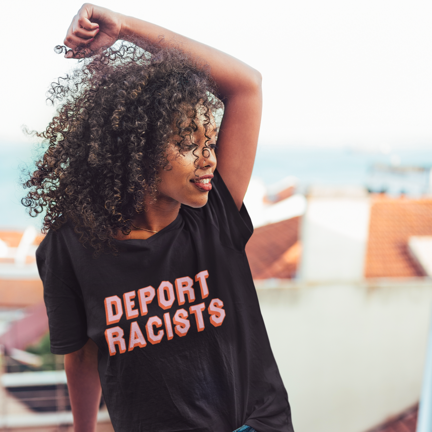 Black feminist t shirt boldly advocating "Deport Racists" in peach writing - Shop Feminist Apparel