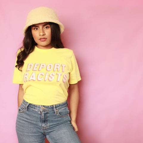 Yellow feminist t shirt boldly advocating "Deport Racists" in peach writing