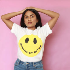 White feminist t shirt boldly stating "Feminist Bitch" with a yellow smiley face