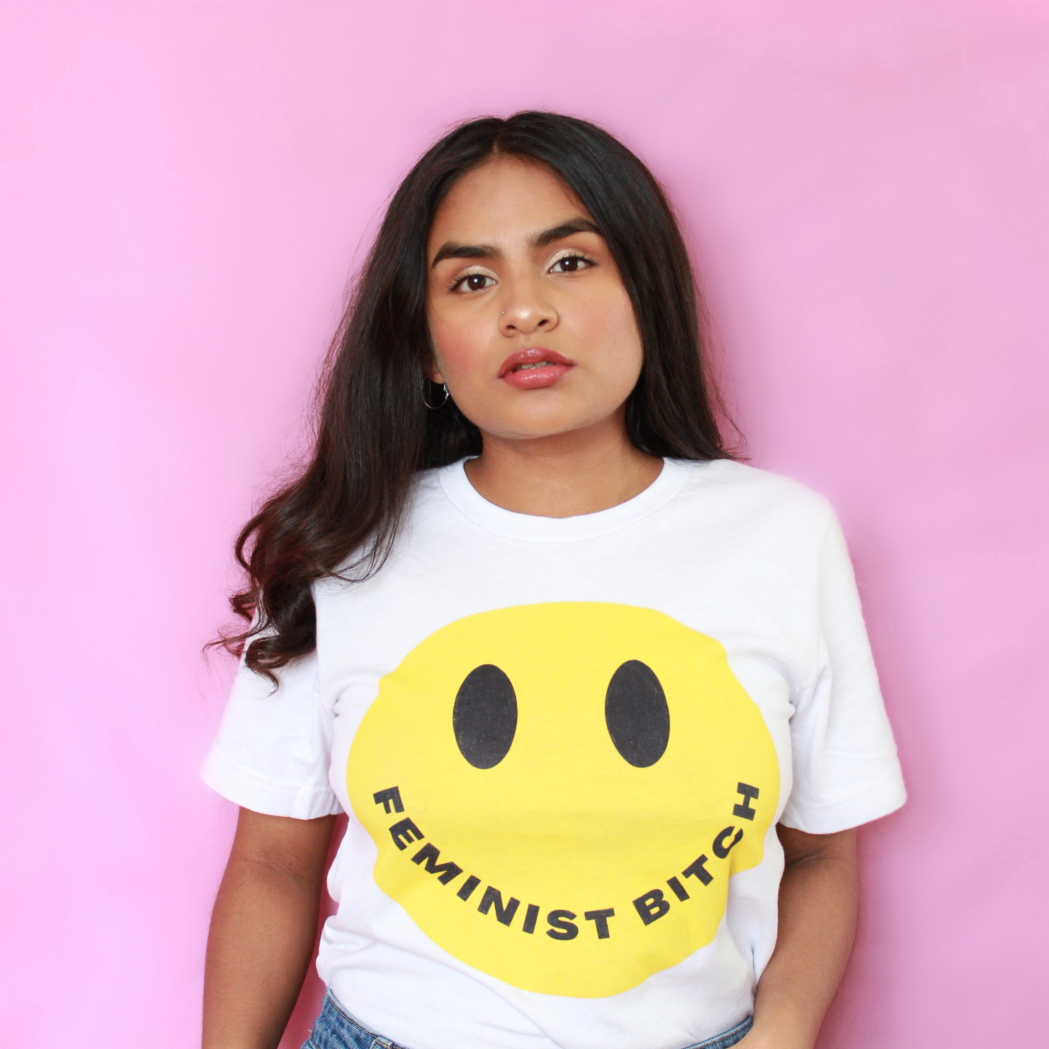 White feminist t-shirt conveying: "Feminist Bitch" with a yellow smiley face