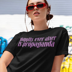black feminist tee that says happily ever after is propaganda in lowercase purple writing- shop Feminist Trash for terrific feminist clothing, pride merch and political tshirts.