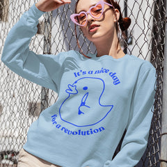 light blue political sweatshirt that says its a nice day for a revolution in blue retro writing featuring an illustration of a duck holding a knife. Shop Feminist Trash for political clothing, pride merch and feminist shirts